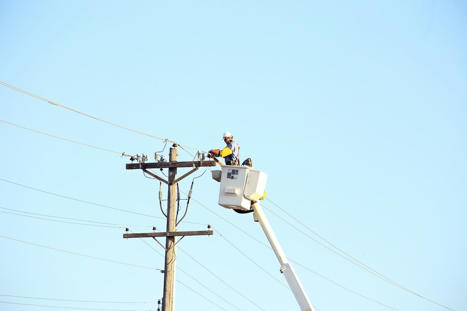 Utility lineman on bucket truck working on power lines during daytime